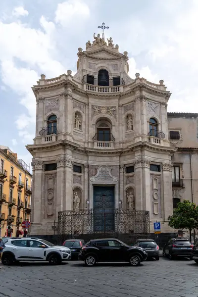 Catania, Sizilien - İtalya - 04-15-2025: Catania, Sicilya 'daki Barok kilise cephesi kemerli pencereler, oyuklar, işlenmiş demir çitler, balkonlar ve taş oymalar.