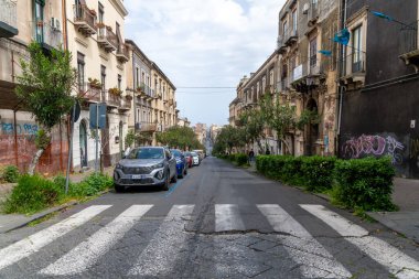 Catania, Sizilien - İtalya - 04-15-2025: Catania 'da park halindeki arabalar, ağaçlar ve tarihi binalarla dolu uzun şehir caddesi.