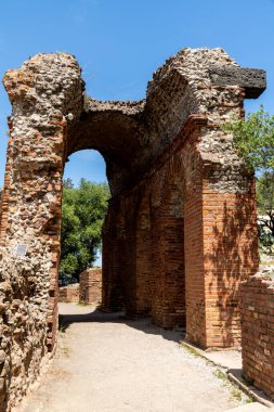 Taormina, Sizilien - İtalya - 05-04-2025: Mavi gökyüzünün altındaki Taormina antik yapısından taş kemer ve tuğla duvarlar, korunmuş yapı ayrıntılarını ve dokulu yapıyı gösteriyor