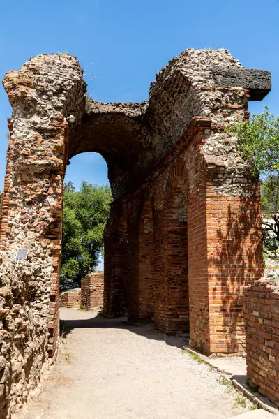 Taormina, Sizilien - İtalya - 05-04-2025: Mavi gökyüzünün altındaki Taormina antik yapısından taş kemer ve tuğla duvarlar, korunmuş yapı ayrıntılarını ve dokulu yapıyı gösteriyor