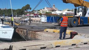 Cagliari - Sardinien - Italien - 03-10-2025: İşçiler, vinç kaldırma prosedürlerine hazırlık niteliğinde Peri Masalı adlı bir yelkenliyi Cagliari limanına götürdüler