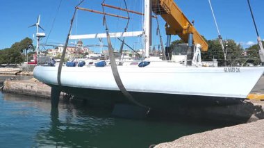 Cagliari - Sardinien - Italien - 03-10-2025: Penelope adlı bir yelkenli vinç kullanılarak liman sularına indirildi, arka planda işçiler ve binalar görülebiliyor..