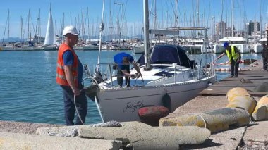 Cagliari - Sardinien - Italien - 03-10-2025: İşçiler, vinç kaldırma prosedürlerine hazırlık niteliğinde Peri Masalı adlı bir yelkenliyi Cagliari limanına götürdüler