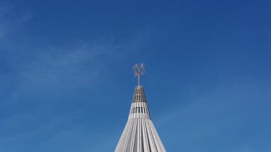 Santuario Madonna delle Lacrime 'in kulesi, kendine özgü haçı ve dikey mimari çizgileriyle mavi gökyüzüne karşı yükselir..