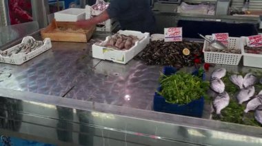 Syrakus, Sizilien - İtalya - 04-09-2025: Siraküza 'daki deniz ürünleri pazarında satılığa çıkarılan taze balık, kabuklu deniz ürünleri ve otlar, müşteriler ve satıcılar görülebilir.
