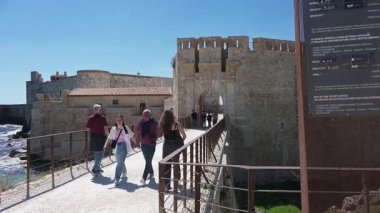 Syrakus, Sizilien - İtalya - 04-09-2025: Ziyaretçiler açık mavi bir günde Castello Maniace 'in tarihi girişine giden köprü boyunca yürüyorlar.