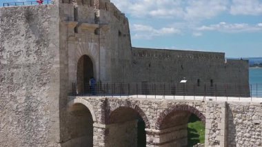 Syrakus, Sizilien - İtalya - 04-09-2025: Castello Maniace 'in sağlam taş duvarları denize bitişik, dalgalar yavaşça aşağıdaki kayalık kıyı şeridine çarpıyor.