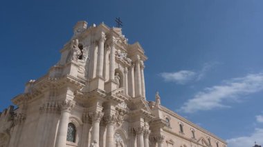 Syrakus, Sizilien - İtalya - 04-08-2025: Barok katedral cephesi ve halka açık meydanda gün ışığında mavi gökyüzü altında yürüyen, oturan veya toplanan insanlar.