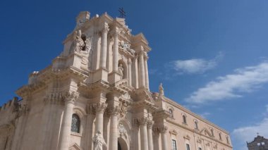 Syrakus, Sizilien - İtalya - 04-08-2025: Syracuse Katedrali 'nin barok cephesi basamaklarda ve meydanda toplanan sütunlar, heykeller ve insan grupları da dahil olmak üzere ayrıntılı olarak gösteriliyor.