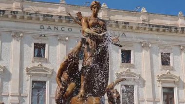 Syrakus, Sizilien - İtalya - 04-08-2025: Syracuse 'deki Diana Çeşmesi, açık mavi gökyüzü altında tarihi Palazzo Sicilya önünde mitolojik heykeller ve su jetleri barındırıyor..