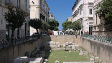 Syrakus, Sizilien - İtalya - 04-08-2025: Syracuse 'deki Porta Urbica' nın antik taş blokları ve temelleri, kentsel duvarlar ve kısmen görünür şehir binalarıyla çevrili.