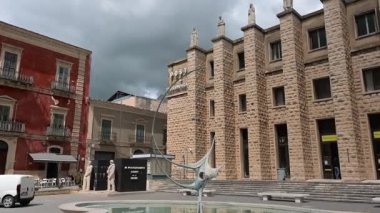 Ragusa, Sizilien - İtalya - 04-03-2025 Redaktionell: Ragusas postahane cephesinde uzun taş sütunlar, heykeller ve halk meydanındaki çeşmedeki modern heykel.