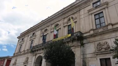 Ragusa, Sizilien - İtalya - 04-03-2025 Redaktionell: Sütunlar, balkonlar, bayraklar, kemerli girişler ve ayrıntılı taş süslemeler içeren Ragusas tarihi belediye binası cephesi.