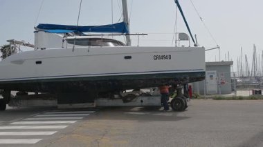 Cagliari - Sardinien - Italien - 03-14-2025: Bakım ve teftiş için liman bölgesine doğru giden liman yolunun karşısındaki tekerlekli platformda çalışan işçiler rehberi.