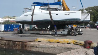 Cagliari - Sardinien - Italien - 03-14-2025: Bir askıya alınmış katamaran rıhtımdaki limandan kaldırıldıktan sonra yavaşça bir nakliye karavanına indirildi.