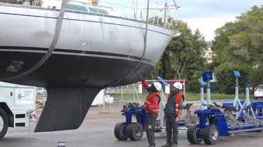 Cagliari - Sardinien - Italien - 03-12-2025: İşçiler daha önce kuru rıhtım sırasında destek çerçevesiyle temas halinde olan yelkenli teknesinin gövdesini kazıyor, kumlanıyor ve yeniden boyuyorlar.
