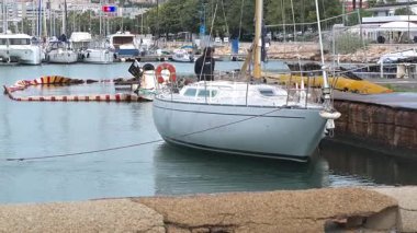 Cagliari - Sardinien - Italien - 03-12-2025: Bir yelkenli, mürettebatın liman kenarındaki konumlarını izlemek üzere küçük bir pilot botu tarafından yavaşça limana çekiliyor..