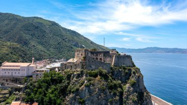 Scilla - Kalabrien - 05-27-2025: Castello Ruffo di Scilla denizin üzerindeki kayalık uçurumdan yükseliyor, tepe, deniz feneri, kilise ve arka planda görünen Scilla kasabası.