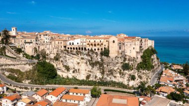 Tropea - Kalabrien - İtalya - 05-28-2025: Calabria 'daki Tropea' nın tarihi binaları, mavi gökyüzü ve ön plandaki çatıları ile denize bakan dik bir uçuruma tünemişti..