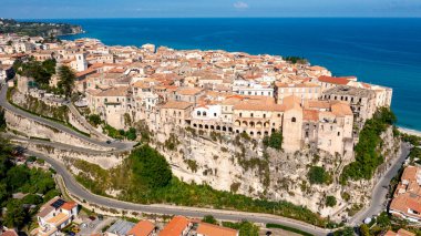 Tropea - Kalabrien - İtalya - 05-28-2025: Arka planda tarihi uçurum kenarı binaları, dolambaçlı yolları, terasotta çatıları ve mavi denizi bulunan Tropea 'nın havadan görünüşü.