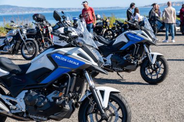 Reggio Calabria - Kalabrien - 05-18-2025: Reggio Calabria 'daki Seçkin Centilmenler' de polis motosikletleri, arka planda kalabalıklar ve bisikletlerle kıyıya yakın park edilmiş..
