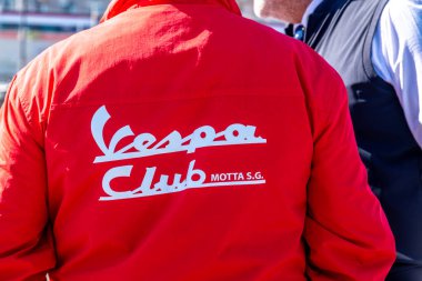 Reggio Calabria - Kalabrien - 05-18-2025: Kırmızı Vespa Club Motta S.G. ceketinin bir kişi tarafından giyilmesi, arkasında beyaz harfler ve yanında başka bir uygun kişi.