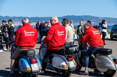 Reggio Calabria - Kalabrien - 05-18-2025: Reggio Calabria 'da Seçkin Beyefendiler Turuna katılanlar, kırmızı Vespa Kulübü ceketleri giyiyor ve klasik scooterların üzerinde oturuyorlar.