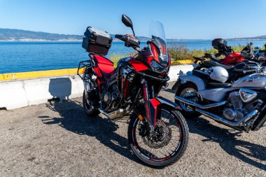 Reggio Calabria - Kalabrien - 05-18-2025: Bir sonraki kıyı bariyerinin yanına park edilmiş kırmızı macera motosikleti