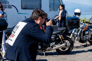 Reggio Calabria - Kalabrien - 05-18-2025: Motosiklet etkinliğinde fotoğraf çeken kadın ve park halindeki motosikletler, İtalya 'nın güneyindeki Reggio Calabria' da çekildi.