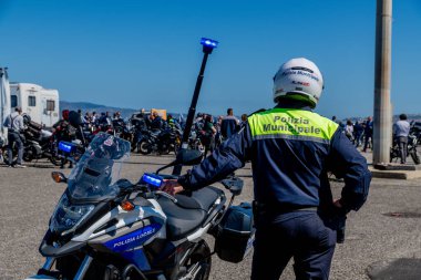 Reggio Calabria - Kalabrien - 05-18-2025: Municipal police officer standing beside patrol motorcycle during the Distinguished Gentlemans Ride in Reggio Calabria, Italy, on a sunny day.