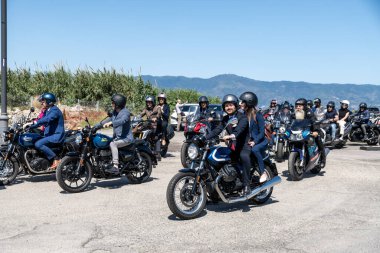 Reggio Calabria - Kalabrien - 05-18-2025: Resmi giyinmiş motosikletçiler, açık bir dağ manzaralı bir günde Reggio Calabria 'da gezinen seçkin beyefendilere katılıyorlar.