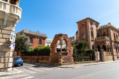 Reggio Calabria - Kalabrien - 05-22-2025: Gotik kemerli kırmızı tuğla binalar ve güneşli bir günde Reggio Calabria 'da dekoratif taş elementler, sokak seviyesinden yakalandılar.