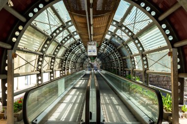 Reggio Calabria - Kalabrien - 05-22-2025: Reggio Calabria 'da cam paneller, metal kirişler ve doğal gün ışığında fabrikalarla çerçevelenen kapalı yürüyen merdiven tünelinin iç görünümü.