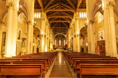 Reggio Calabria - Kalabrien - 05-22-2025: Reggio Calabria Katedrali 'nin iç manzarası ahşap sıralar, kemerli kolonlar, avizeler ve uzak sunakla süslü tavanlar gösteriyor.