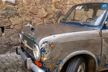 Scilla - Kalabrien - 05-27-2025: Paslı Fiat kaputu ve önde görünen krom sıçan figürü, Scilla, Calabria 'da, eski taş duvar arka planına karşı.