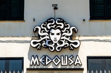 Scilla - Kalabrien - 05-27-2025: Yılan tüylü siyah ve beyaz Medusa işareti ve Scilla, Kalabrien 'deki pencerelerin altındaki ışık cephesine monte edilmiş şekillendirilmiş harfler.