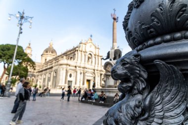 Catania, Sizilien - İtalya - 04-15-2025: Catania 'nın kalabalık meydanında SantAgata Katedrali ve Fil Çeşmesi ile dekoratif siyah aslan heykelinin ön görünümü.