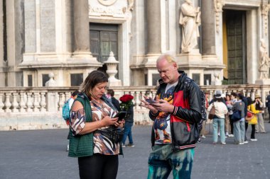 Catania, Sizilien - İtalya - 04-15-2025: Diğer insanlar arka planda toplanırken, Sicilya 'nın Catania kentindeki SantAgata Katedrali önünde iki turist ayakta duruyor.