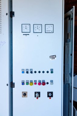 Catania, Sizilien - İtalya - 04-22-2025: Analog göstergeler, düğmeler ve anahtarlarla donatılmış büyük bir beyaz kontrol dolabının ön görünümü, teknik sistemleri izlemek için kullanılır.