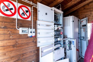 Catania, Sizilien - İtalya - 04-22-2025: Tahta bir kulübenin içindeki kablolar ve anahtarlarla birlikte açık elektrik dolapları ve duvarda belirgin uyarı levhaları.