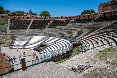 Taormina, Sizilien - İtalya - 05-04-2025: Turistler tarafından ziyaret edilen Taormina, Sicilya 'daki modern beyaz koltukları ve tarihi taş teraslarıyla kısmen restore edilmiş amfi tiyatro.