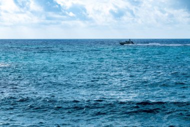 Tropea - Kalabrien - İtalya - 05-29-2025: Parlak güneşli bir öğleden sonra, parçalı bulutlu bir gökyüzünün altında, Tropea, Calabria 'nın turkuaz sularında hızla ilerleyen bir sürat teknesi.