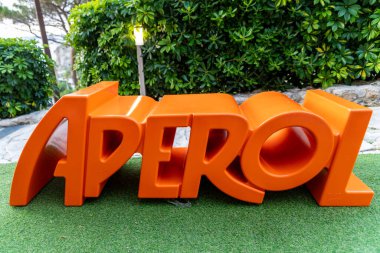 Tropea - Kalabrien - İtalya - 05-29-2025: Tropea, Calabria 'da suni çimlerin üzerine yerleştirilmiş turuncu bir 3D Aperol tabela heykeli. Bu huzurlu yer popüler bir hedef.