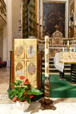 Tropea - Kalabrien - İtalya - 05-30-2025: Tropea, Calabria 'da Chiesa del Gesu' nun içinde, bir mum ve işlemeli kumaş büyük bir dini resmin altında sunağı süslüyor..