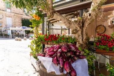 Tropea - Kalabrien - İtalya - 05-30-2025: Tropea, Calabria 'daki bir restoranın dışında çiçek, bitki ve taş kaldırımlarla çevrili taze kırmızı soğanlar sergileniyor.