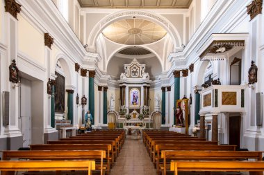 Tropea - Kalabrien - İtalya - 05-30-2025: Tropea, Calabria 'daki San Michele Kilisesi' nin içi, simetrik ahşap sıralar, heykeller ve dini sanat eserleriyle süslü bir sunak göstermektedir..