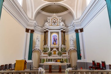 Tropea - Kalabrien - İtalya - 05-30-2025: Tropea, Calabria 'daki San Michele Kilisesi içinde klasik heykeller, çiçek düzenlemeleri ve yukarıda dini bir tablo yer alıyor.