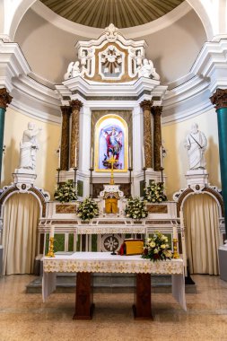 Tropea - Kalabrien - İtalya - 05-30-2025: Tropea, Calabria 'daki Chiesa San Michele' de bulunan mihrapta aziz heykelleri, çiçek süslemeleri ve merkezi bir dini resim yer alıyor..