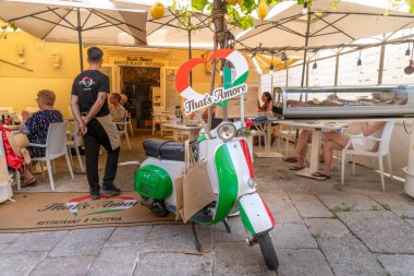 Tropea - Kalabrien - İtalya - 05-30-2025: Bir garson, Tropea, Calabria 'daki açık İtalyan pizzacısının müşterilerinin yanında duruyor..