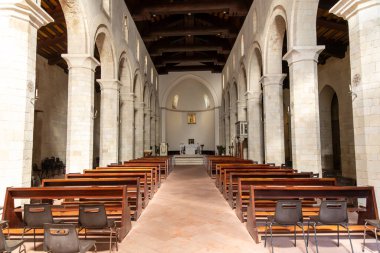 Tropea - Kalabrien - İtalya - 05-30-2025: Tropea, Calabria 'daki Roma katedralinin iç görünümü, taş sütunlar, ahşap sıralar, kubbeli tavan ve sunak alanlarını gösteriyor.